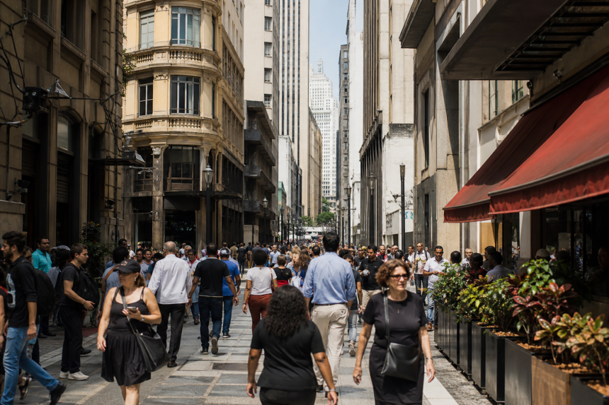 Rua movimentada do Centro de São Paulo com estabelecimentos gastronômicos ao redor