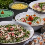 Variedade de pratos da culinária japonesa, incluindo sushis e saladas, dispostos sobre uma mesa.