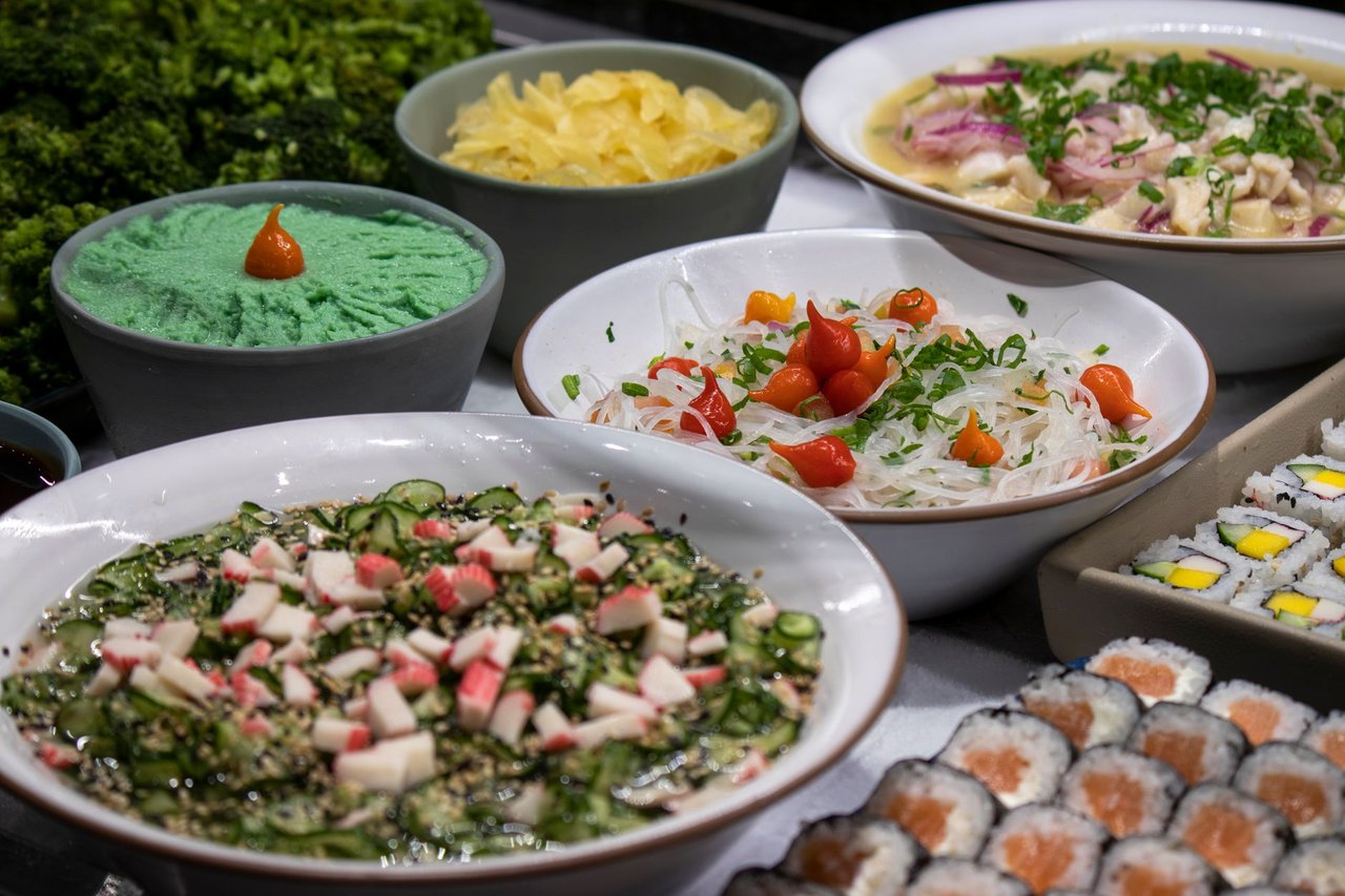 Variedade de pratos da culinária japonesa, incluindo sushis e saladas, dispostos sobre uma mesa.
