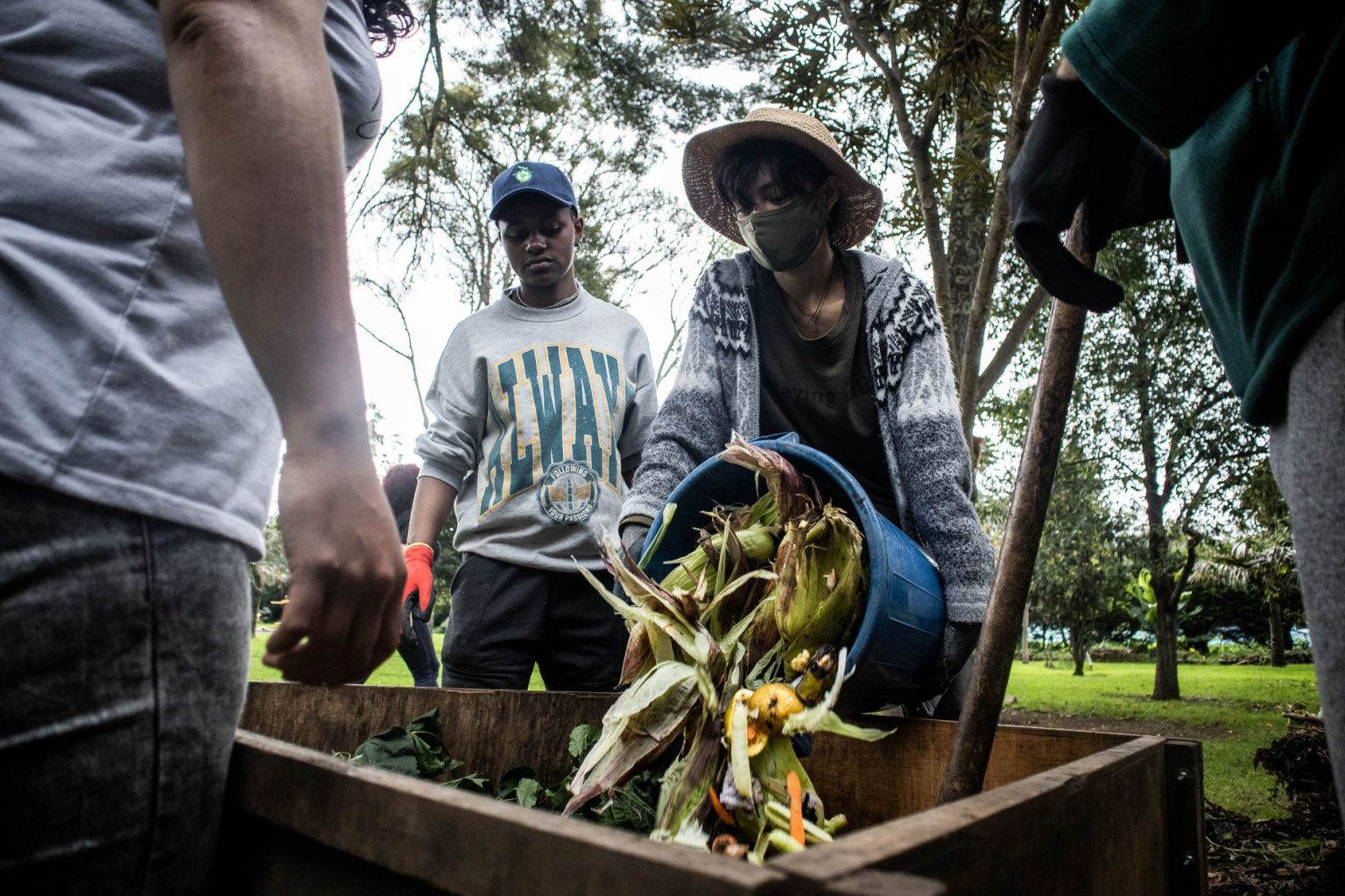 Pessoas participam de uma atividade comunitária de compostagem em um espaço de agricultura urbana.