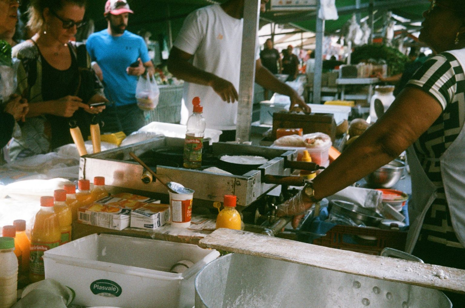 Vendedores e clientes movimentam uma feira de rua em São Paulo, com barracas de comida ao ar livre.