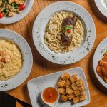 Vista de cima de diversos pratos gourmet brasileiros dispostos sobre uma mesa.