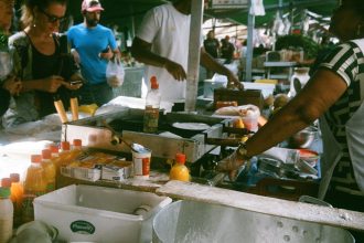 Vendedores e clientes movimentam uma feira de rua em São Paulo, com barracas de comida ao ar livre.